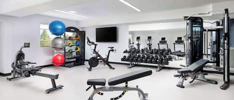 Een moderne sportschool met diverse fitnessapparaten, waaronder loopbanden, hometrainers en gewichten.