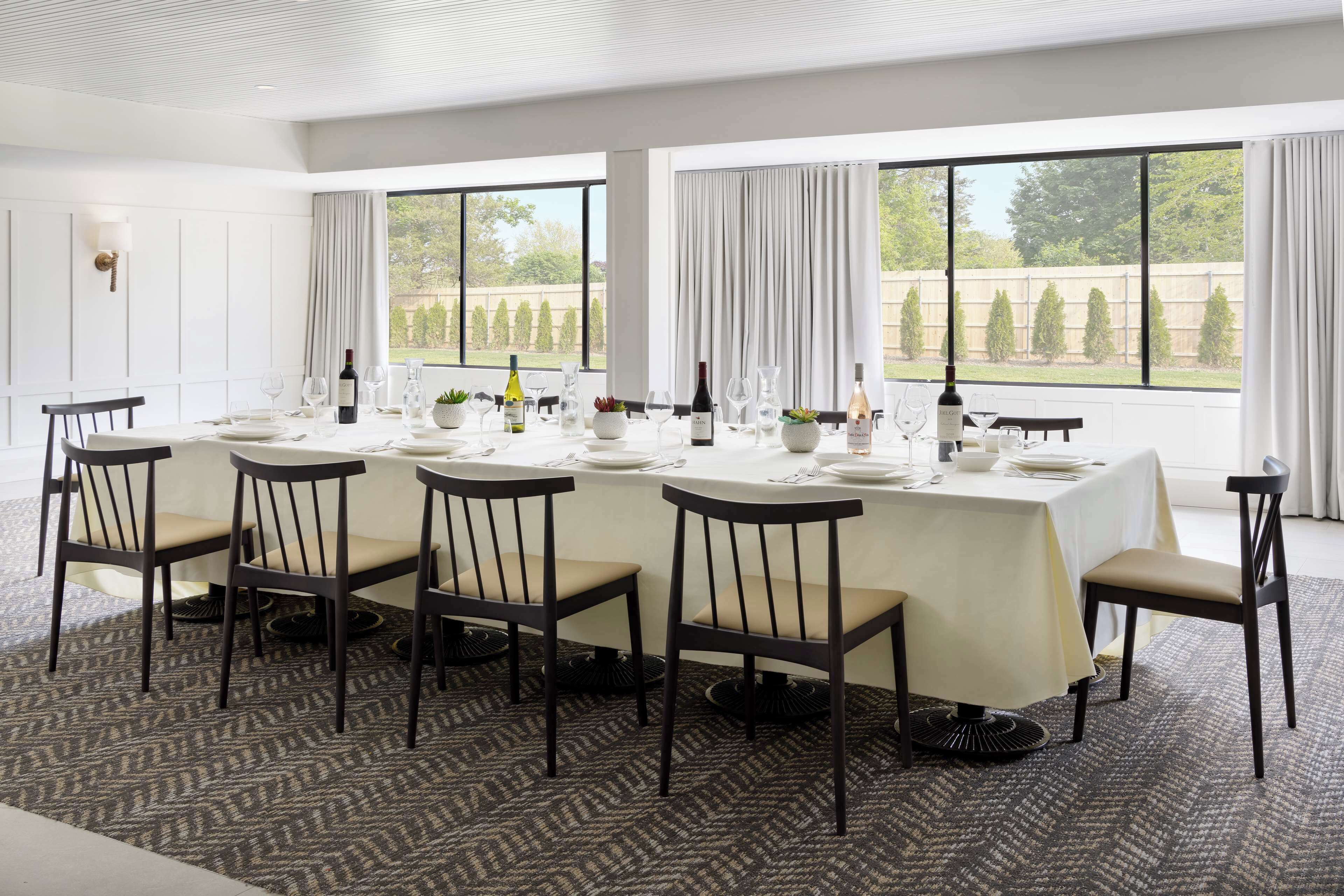 Comedor con una larga mesa dispuesta para seis, ventanas amplias y vistas al exterior.