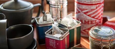 A tray with tea bags, a coffee pot, a jar of jam, and a tin of biscuits.