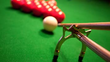 Gros plan d’une queue de billard et de billes sur une surface de feutre verte.