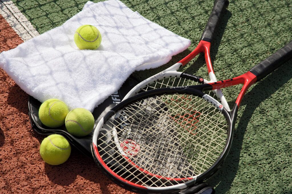 Un campo da tennis con un asciugamano bianco, palline da tennis e una racchetta.
