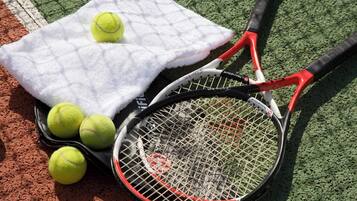 Un campo da tennis con un asciugamano bianco, palline da tennis e una racchetta.