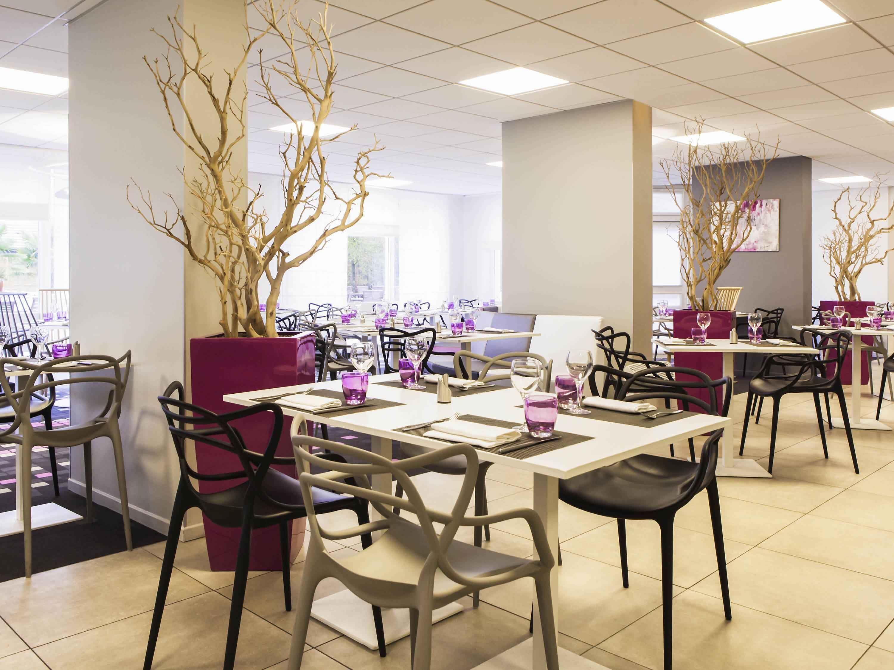 Ein Restaurant mit Tischen und Stühlen, einige mit violetten Gläsern.