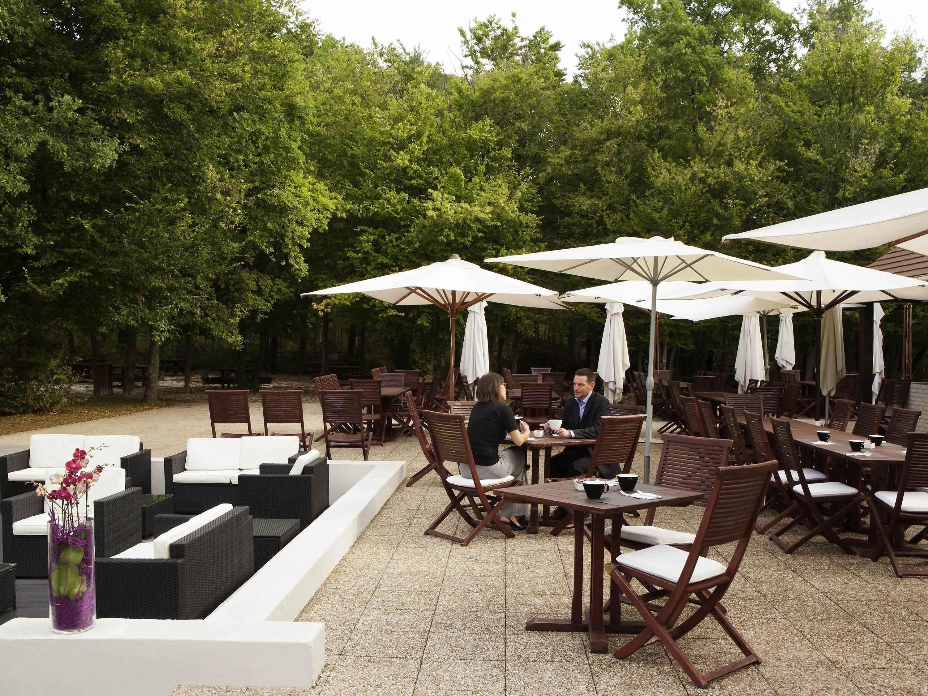 An outdoor seating area with tables and chairs, umbrellas, and a decorative vase.