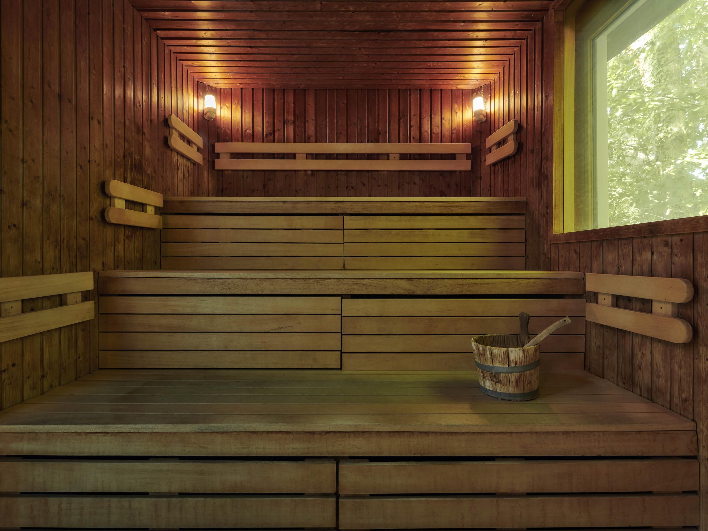 Un sauna en bois avec des bancs et un seau.