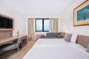 A hotel room with a bed, a desk, a TV, a window with curtains, and a painting on the wall.