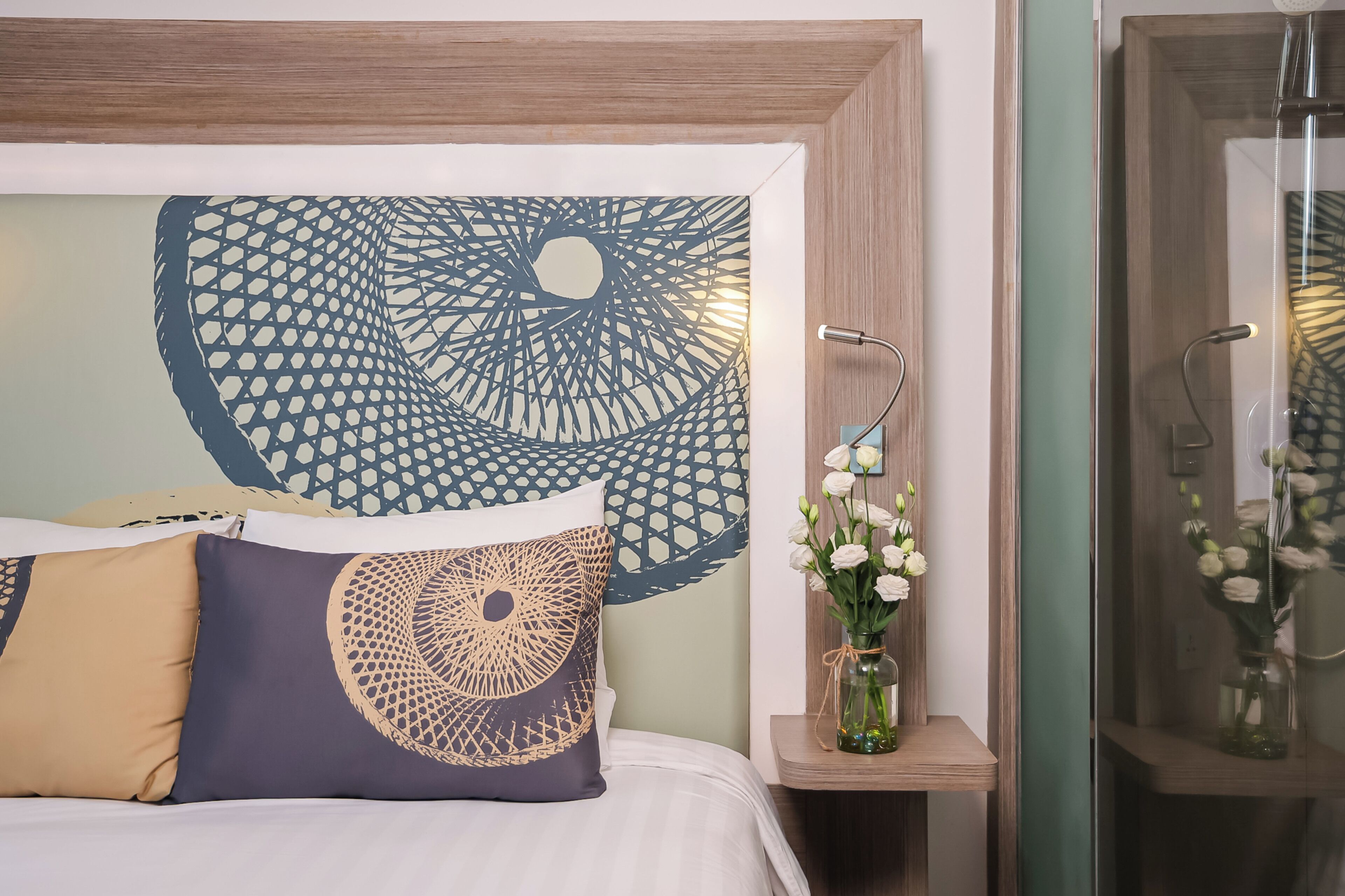 Une chambre à coucher comprenant un lit, une œuvre d’art murale, un vase avec des fleurs et un espace douche.