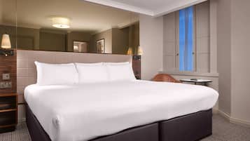 Una habitación de hotel moderna con una cama grande, una mesita y un armario.