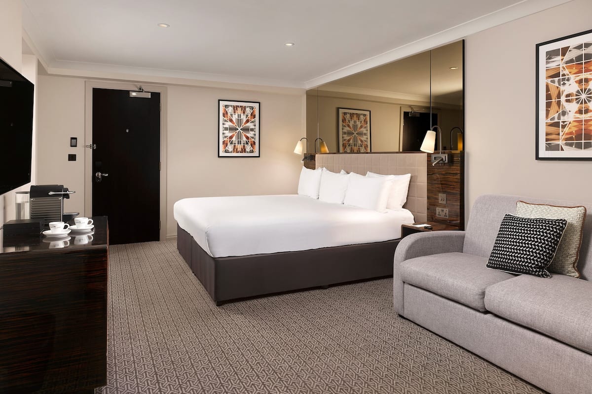 Ett hotellrum med en stor säng, en soffa, ett soffbord och konstverk på väggarna.