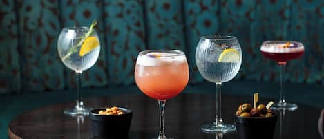 Tres vasos de bebidas sobre una mesa redonda con acabado de madera oscura.