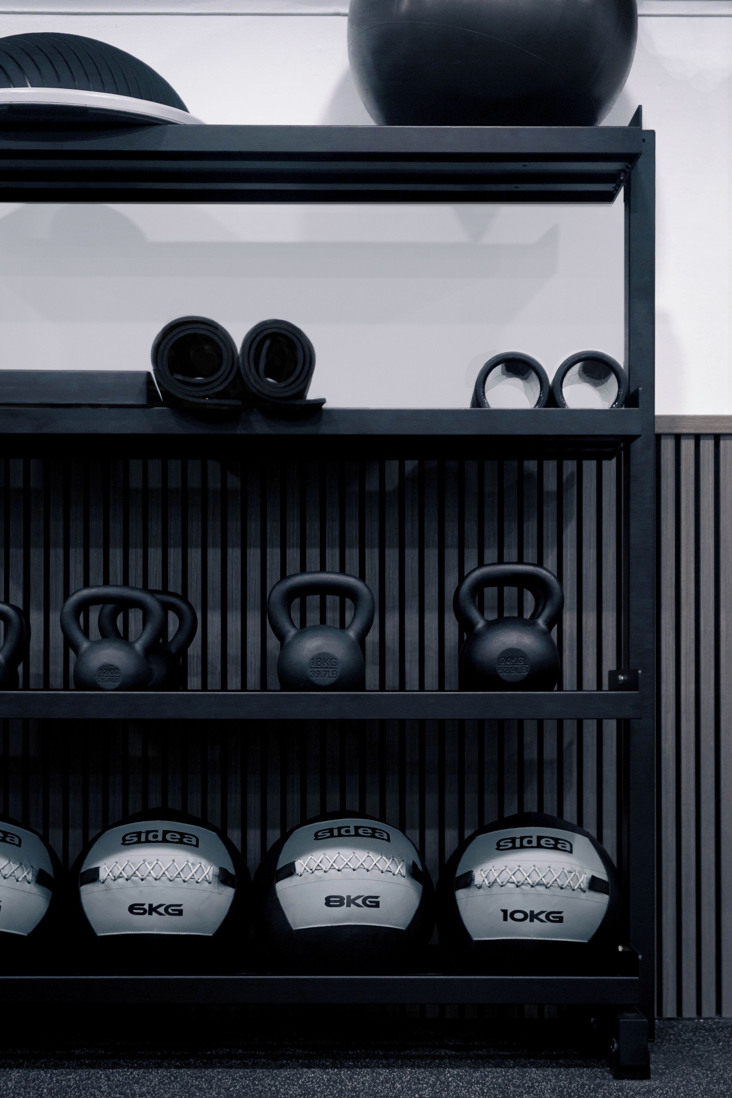 A black shelf with kettlebells and weight plates.