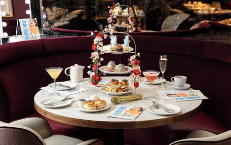 A round table with a tiered dessert stand, plates of food, and a magazine.