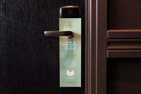 A door with a card that says "SAY NO TO HOUSEKEEPING SAY YES TO GO GREEN" and a request to hang the card on the door before 2am for a voucher.