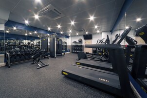 Ein Fitnessstudio mit Laufbändern, Krafttrainingsgeräten und Kurzhanteln.