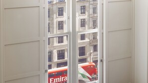 A window with a view of a red bus labeled 'Emira' and a building with balconies. - Strand Palace Hotel (London)