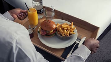 A tray with a burger, fries, a glass of orange juice, and a bottle of water.