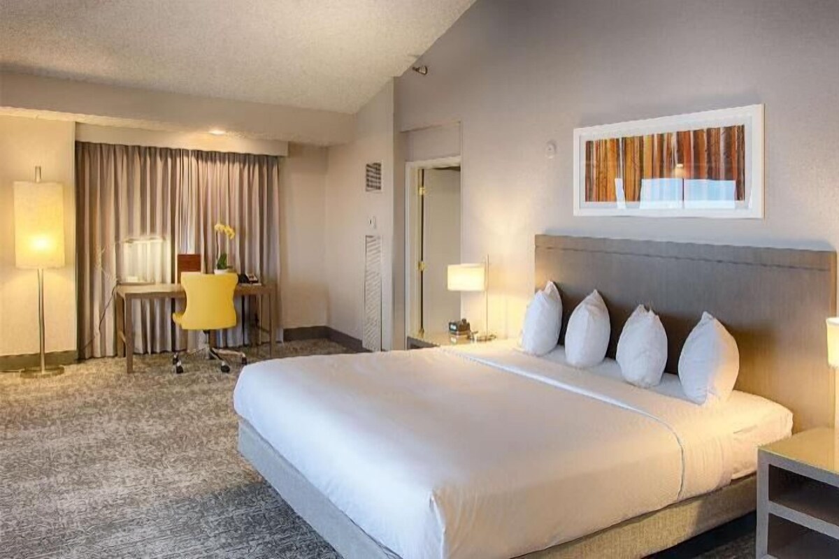 A hotel room with a large bed, bedside tables, a desk, and a chair.