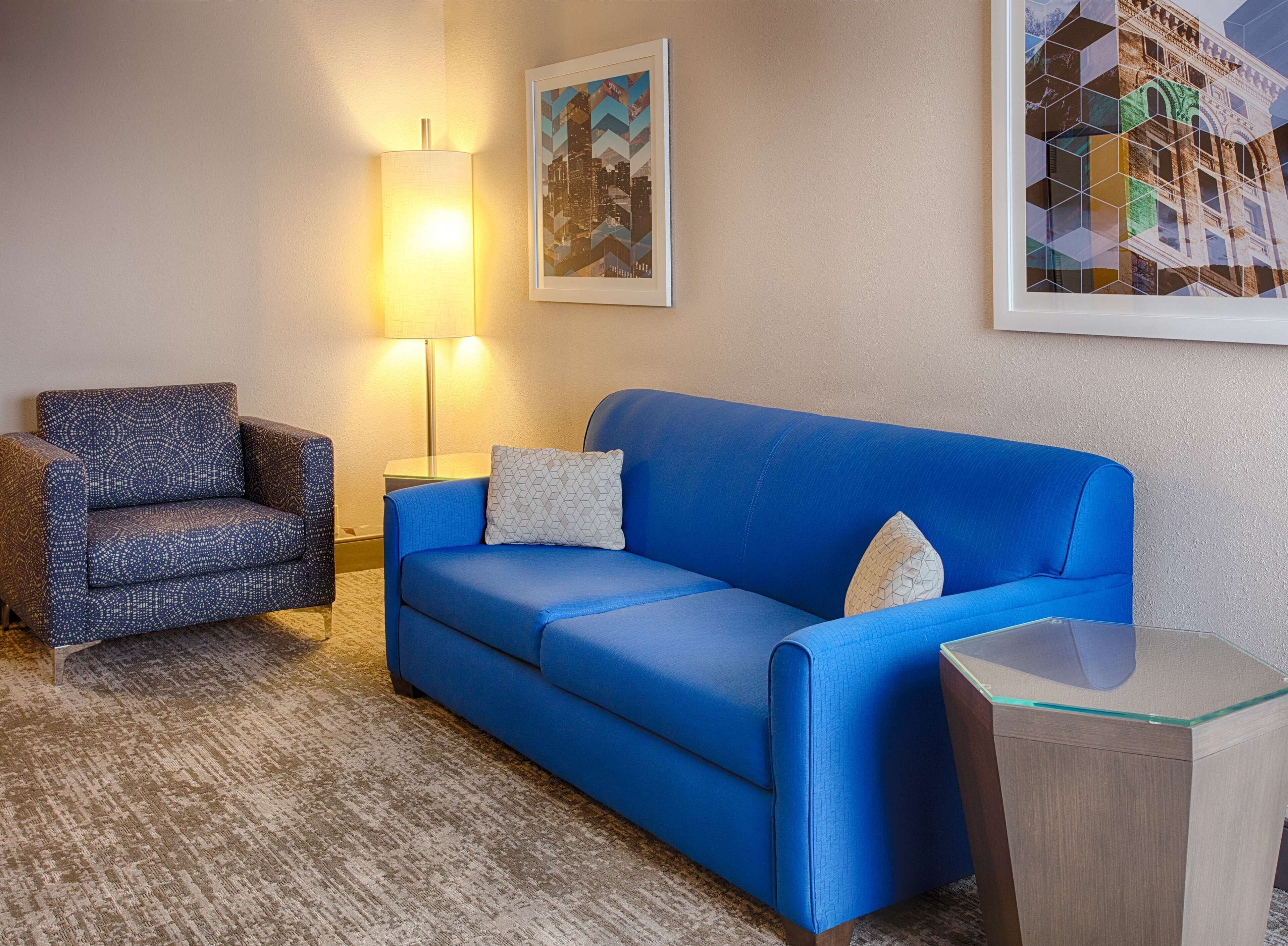 A living room with a blue sofa, patterned armchair, and a lamp.