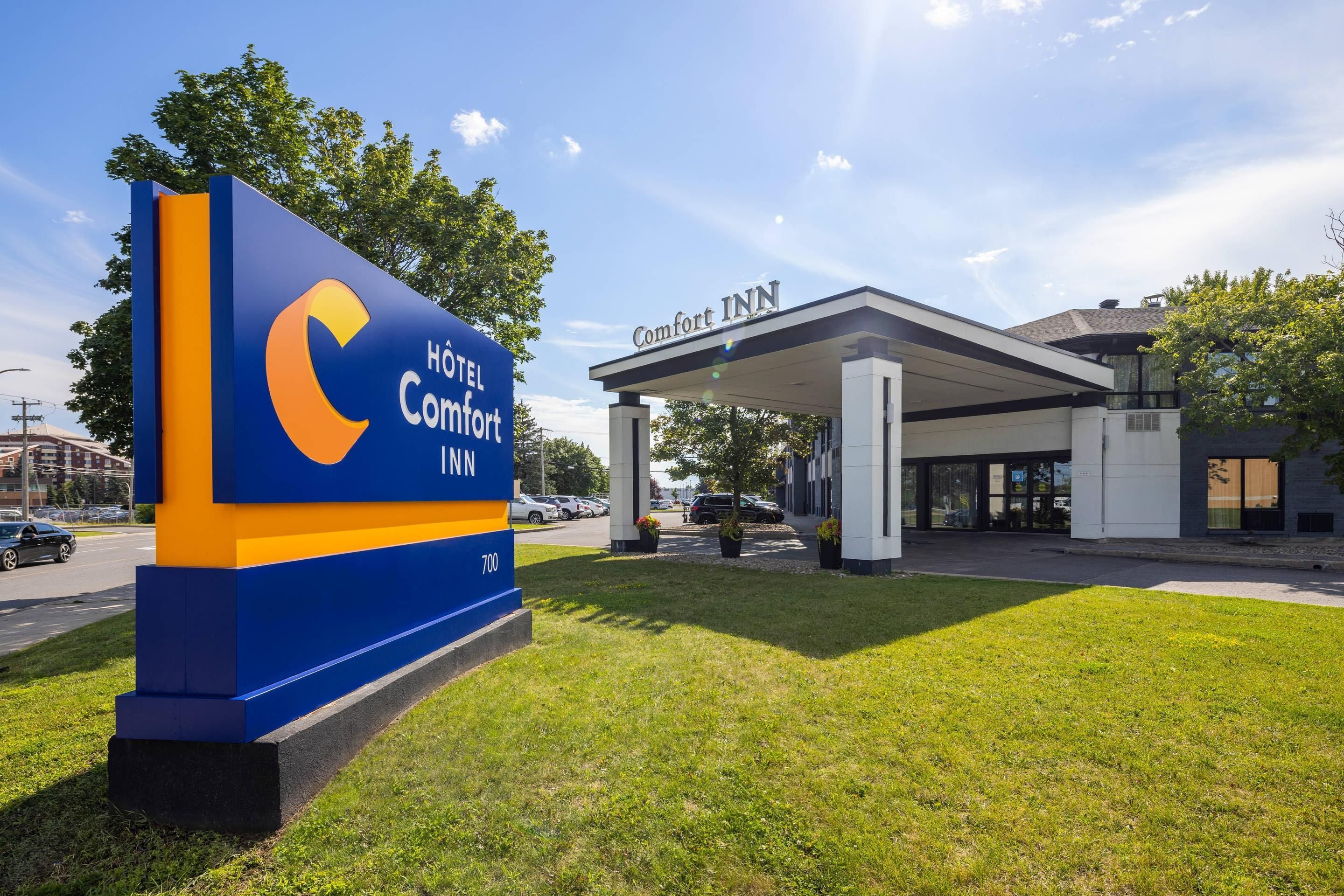 A hotel sign with the name 'Hotel Comfort INN' and a building with a covered entrance.