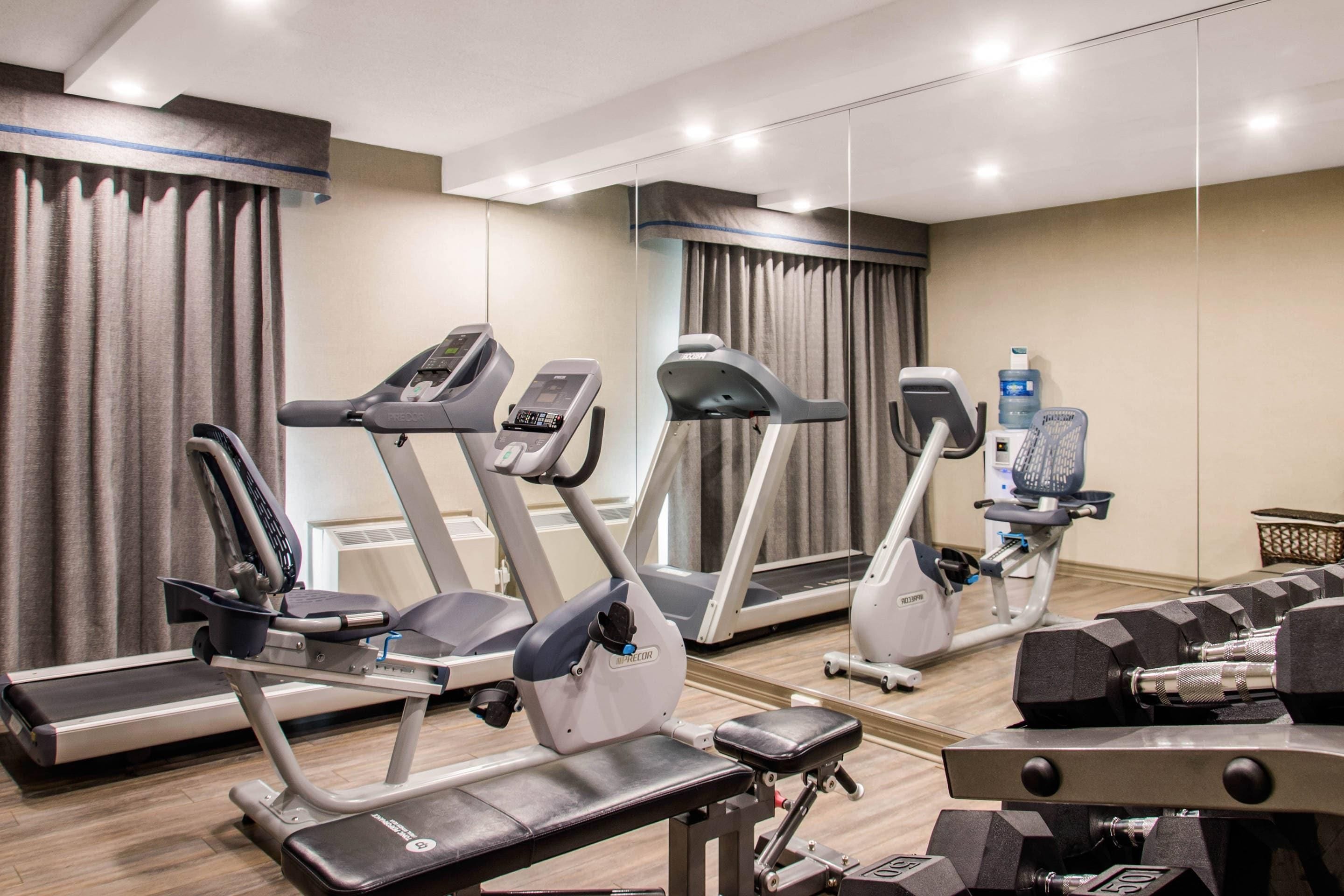 Un gimnasio con cintas de correr, elípticas y equipos de pesas.