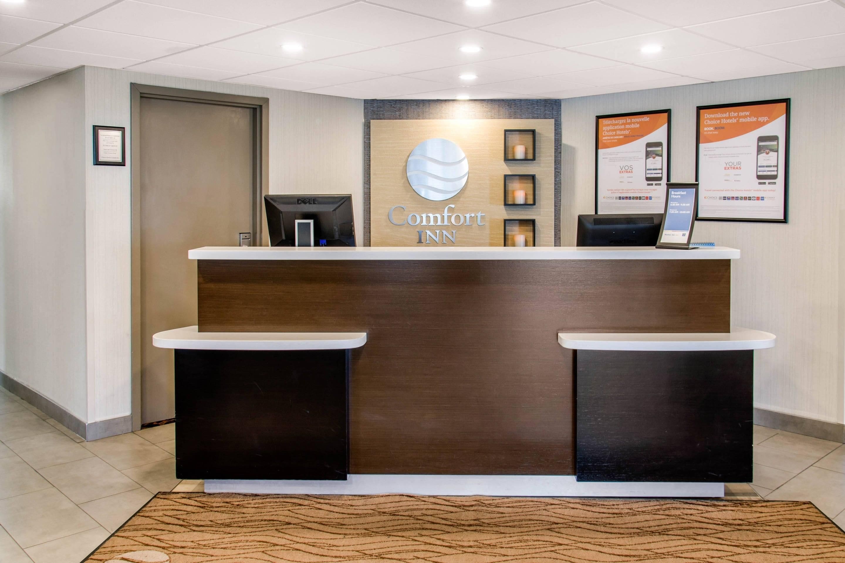 A reception desk with a sign reading 'Comfort Inn' and a digital display for guests.