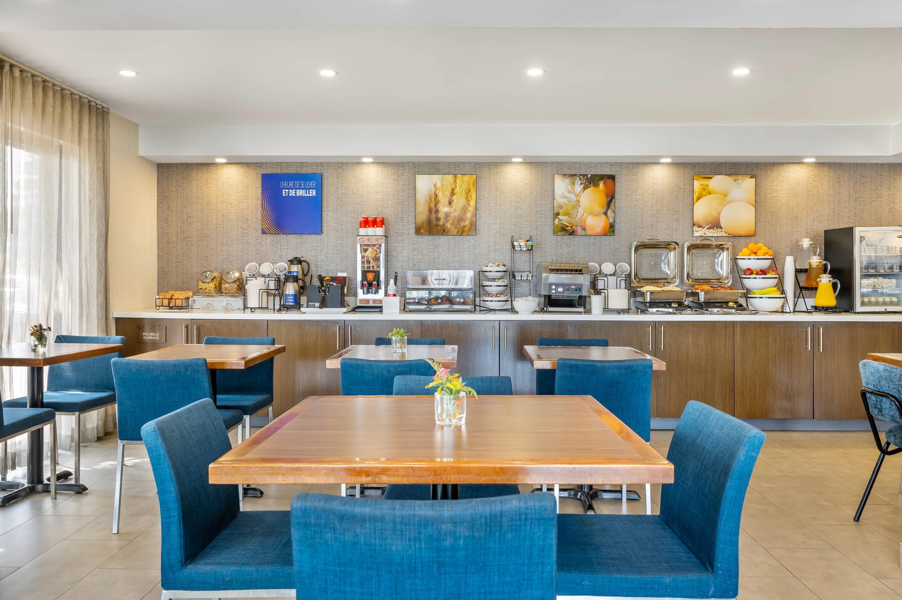 Un moderno comedor con una barra alargada, sillas tapizadas en azul y una mesa de madera.