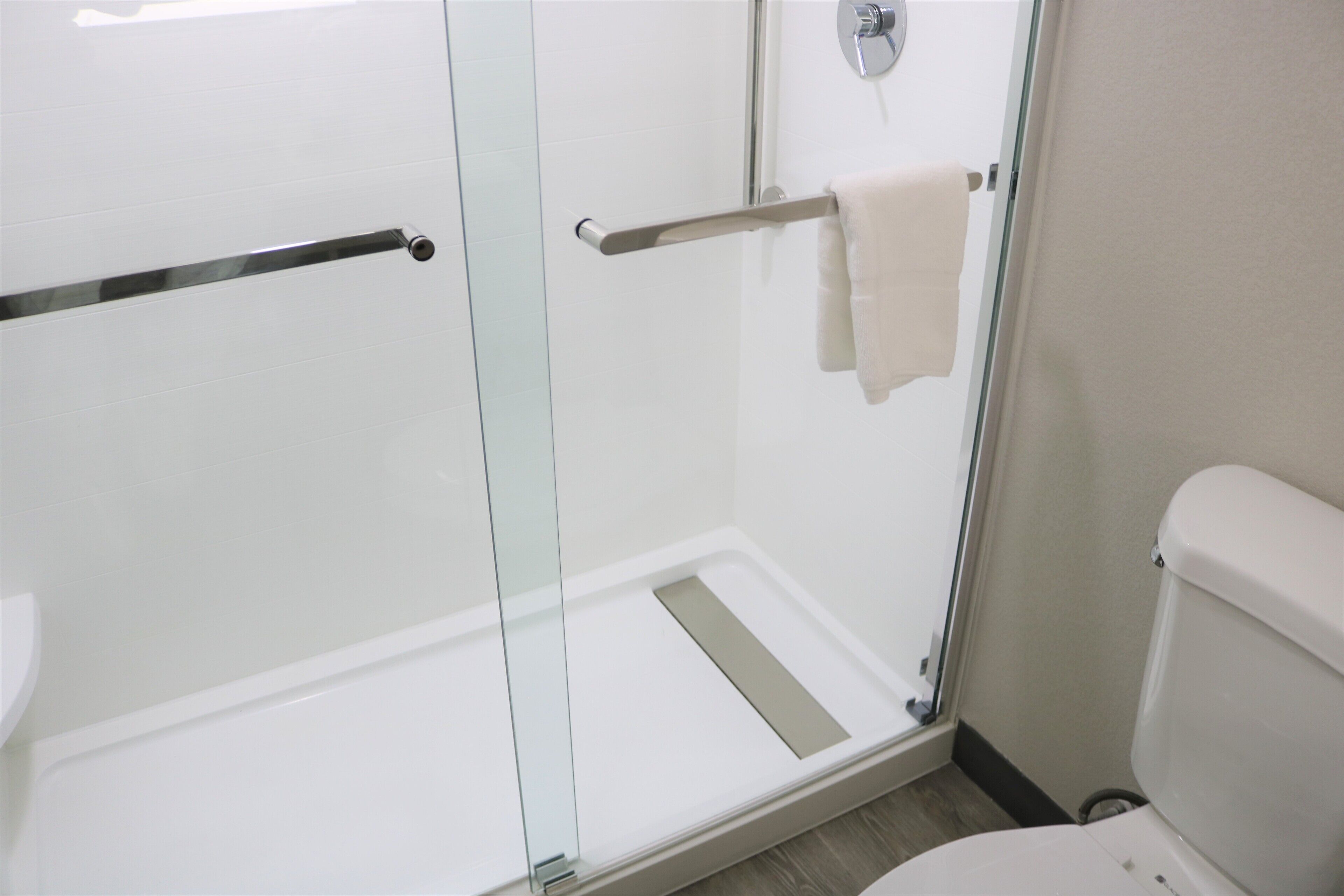 A modern bathroom with a glass shower enclosure, a toilet, and a towel rack.
