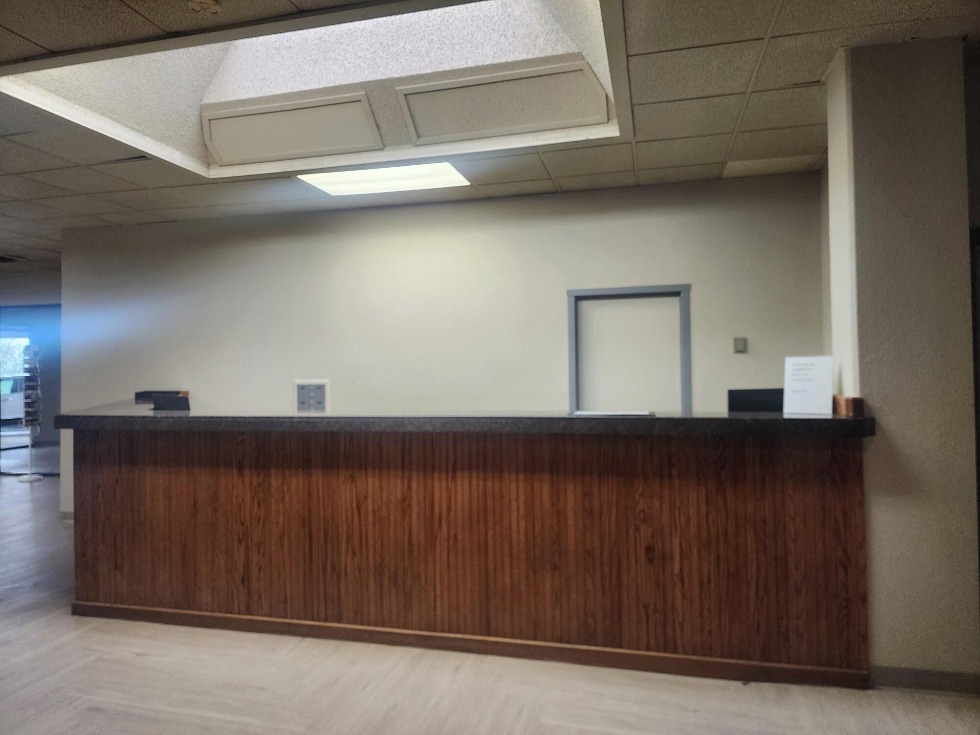 A reception desk with a wooden finish, a door, and a sign on the wall.
