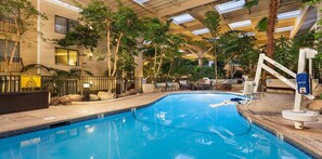 An indoor swimming pool with a tiled edge, surrounded by lounge chairs and a palm tree. - Courtyard by Marriott Concord Walnut Creek (Concord)