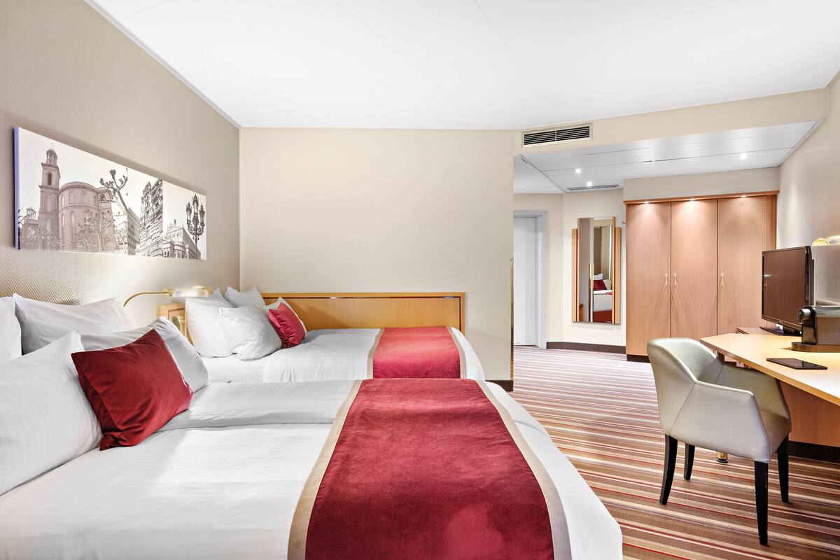 Een hotelkamer met twee bedden, een bureau, een stoel en een televisie.