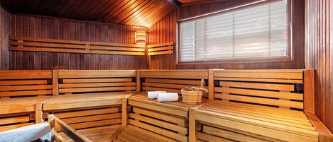 Una sauna con bancos de madera y una pileta de piedra.