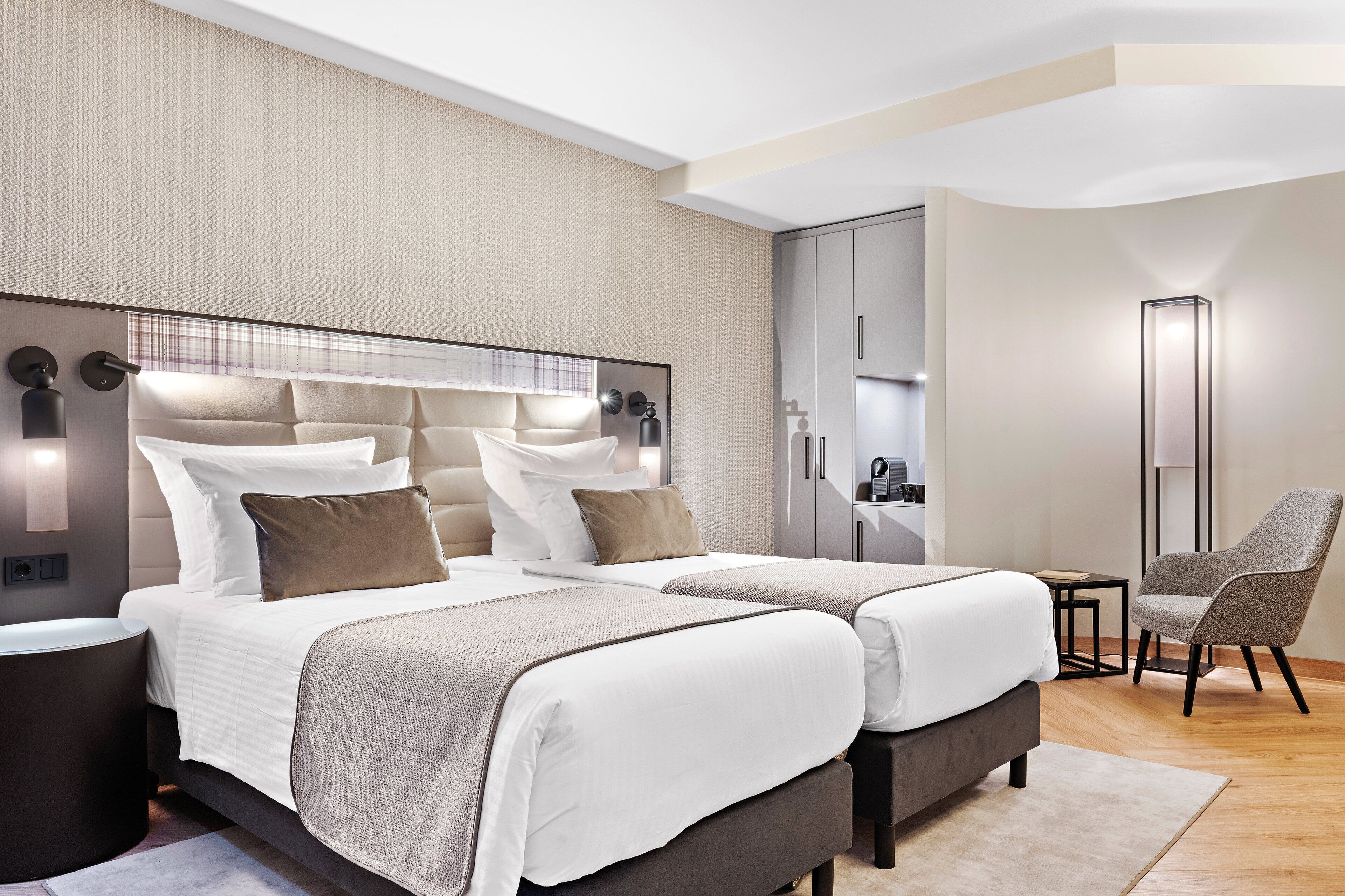 Ein modernes Hotelzimmer mit zwei Betten, einem Schreibtisch und einem Stuhl.