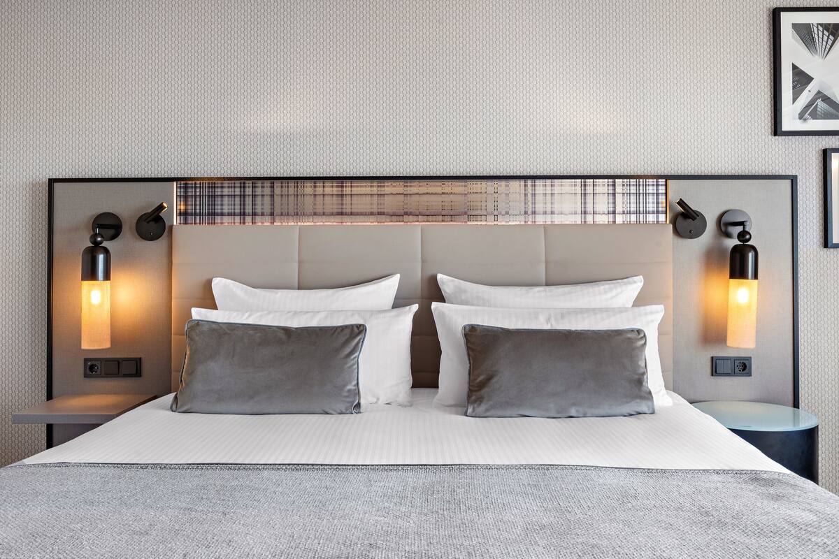 Een moderne hotelkamer met een groot bed, twee nachtkastjes en wandlampen.