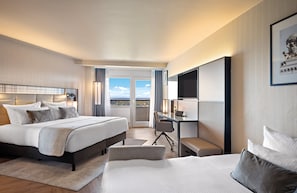 Ein modernes Hotelzimmer mit einem großen Bett, einem Schreibtisch und Blick auf die Stadt.
