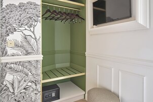 A closet with a green interior, wooden hangers, and a black safe.