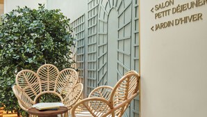 A modern interior with wicker chairs, a wooden table, and a wall with directional signs. - Posy Hotel by Happyculture (Paris)