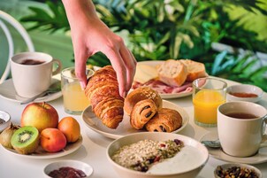 Una tavola per la colazione con croissant, frutta, succo e caffè.