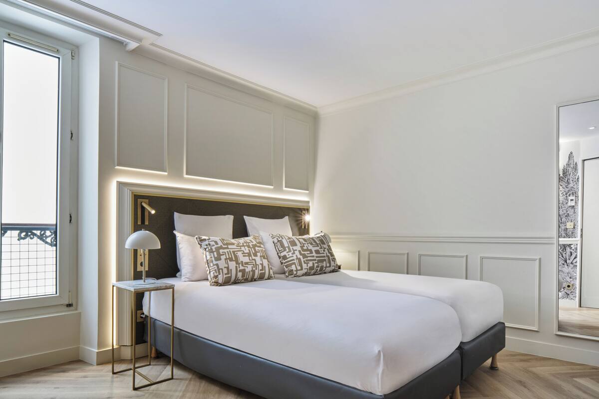 Una camera da letto moderna con un letto grande, lampade ai comodini e vista su un balcone.