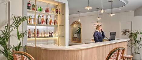 A bar area with a counter, shelves of bottles, and two wicker chairs.