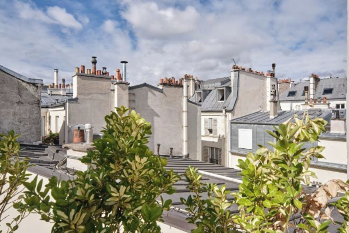 A residential building with multiple chimneys, a visible staircase, and a clear sky.