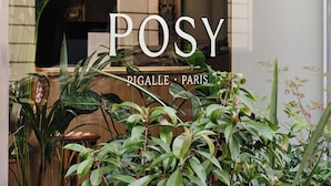 A hotel sign with a plant logo and the name "POSY" in the window. - Posy Hotel by Happyculture (Paris)