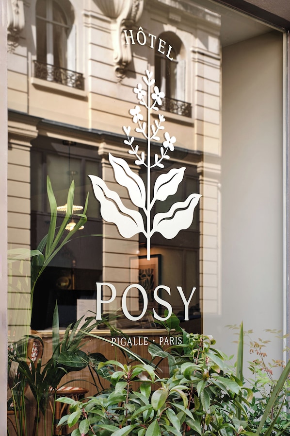 Letrero de hotel con un logotipo de planta y el nombre 'POSY' en la ventana.