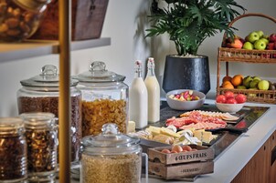Un bufé con diversas opciones de comida, como frutas, quesos y embutidos.