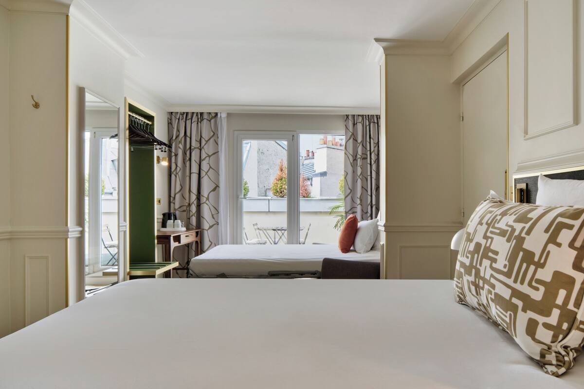 Una camera d'albergo con un letto, una scrivania e vista all'esterno.