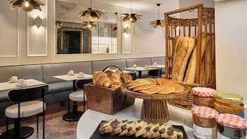 A restaurant interior with seating, a bread display, and jars of jam.