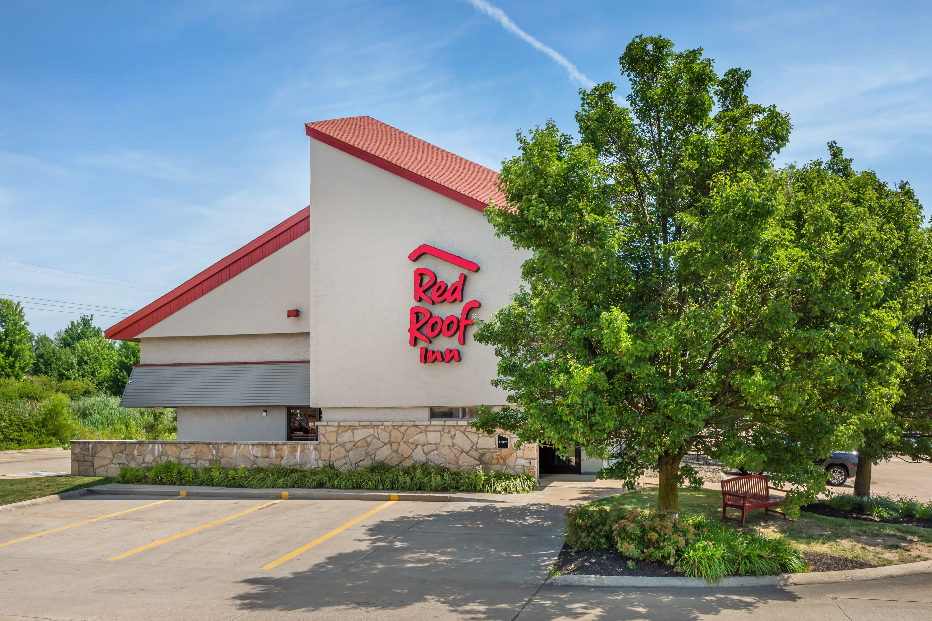 A Red Roof Inn with a stone facade, a red roof, and a parking lot.