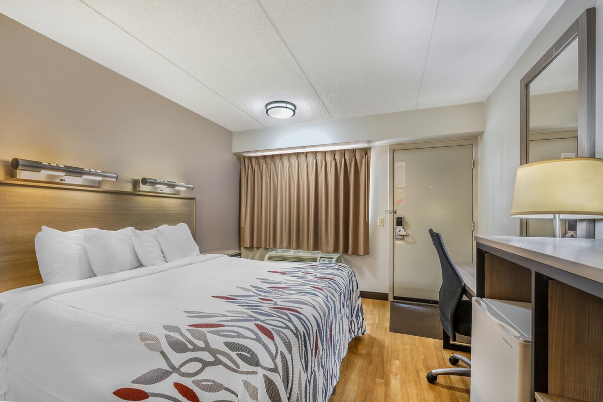 Una camera d'albergo con un letto, una scrivania, una sedia e una porta che dà su un'altra stanza.