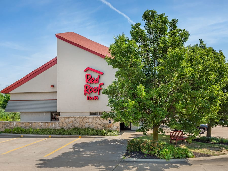 A Red Roof Inn with a stone facade, a red roof, and a parking lot.