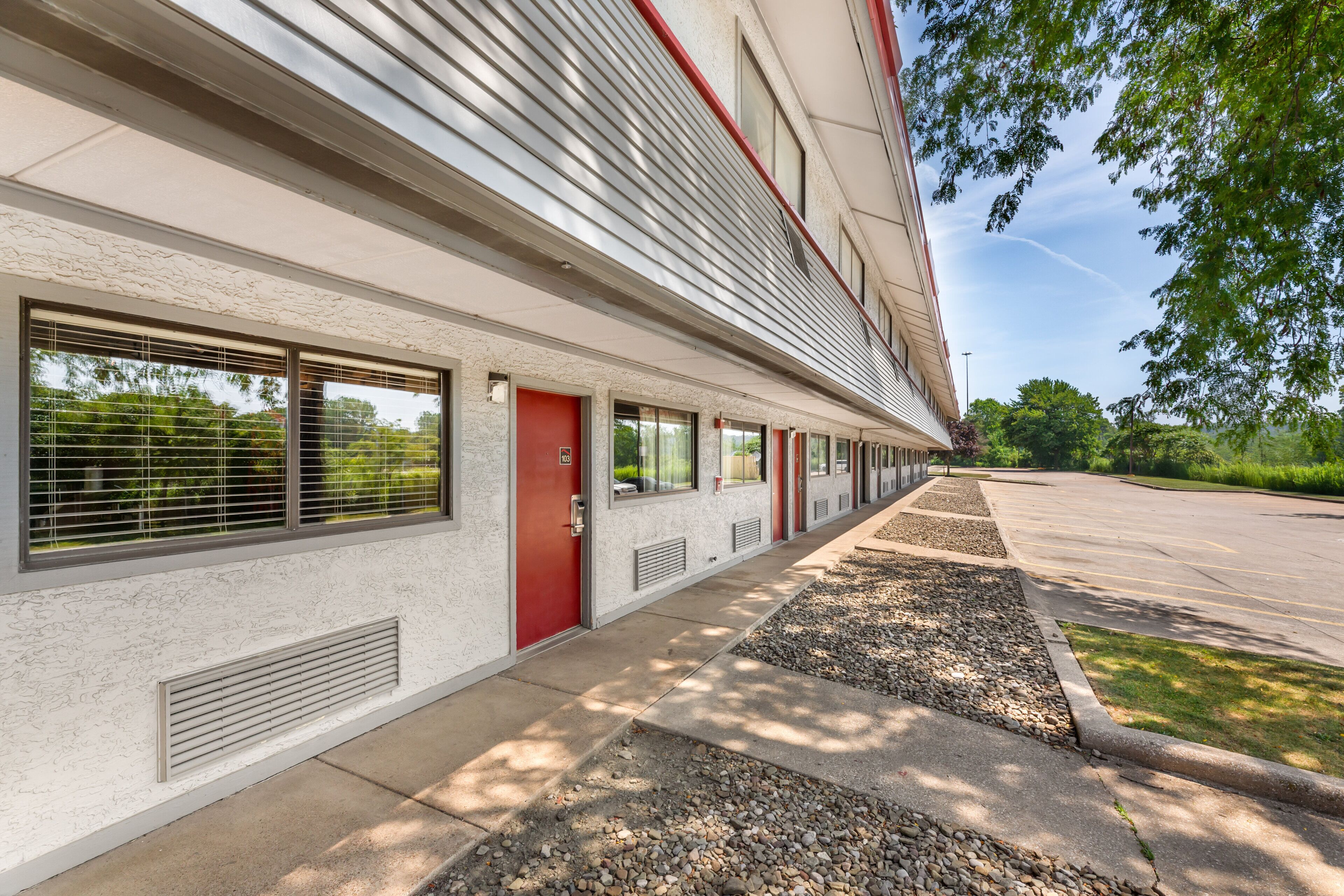 A building with a row of windows, a red door, and a parking lot.
