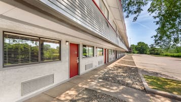 A building with a row of windows, a red door, and a parking lot.